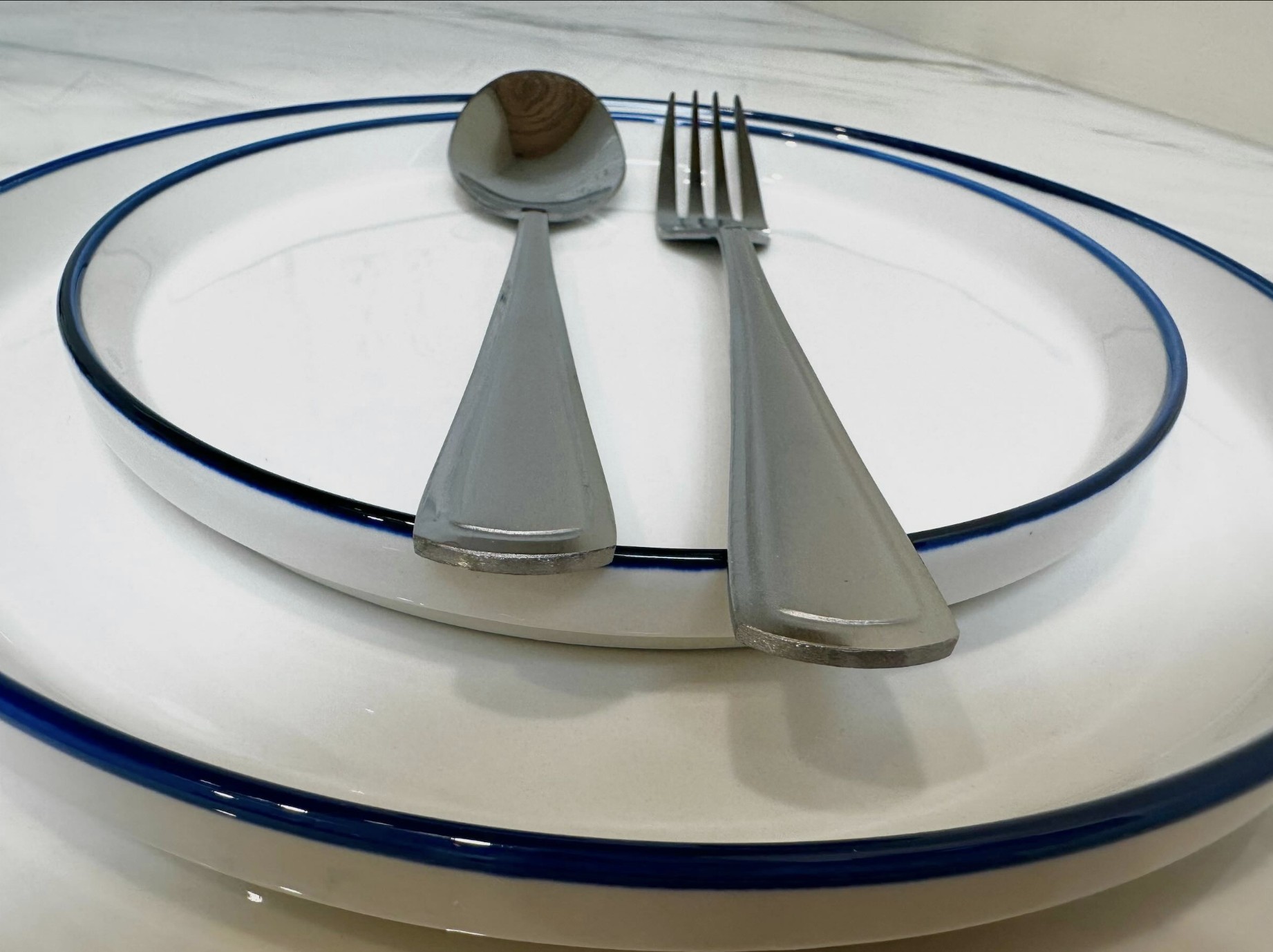 White and navy-trimmed plates with fork and spoon place setting